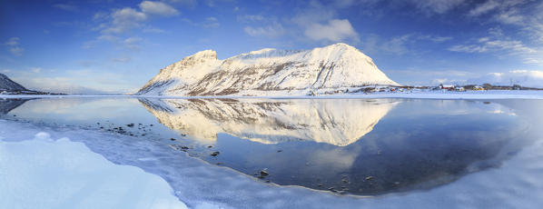 The snow capped mountains reflected in Steiropollen lake at sunrise. Lofoten Islands Northern Norway Europe