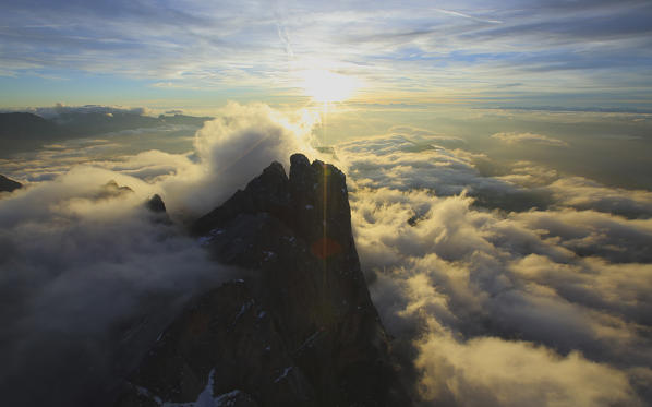 Rays of setting sun light up the summits hidden by clouds. Odle Val Funes Dolomites Trentino Alto Adige South Tyrol Italy Europe