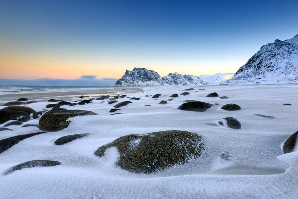 Dawn illuminates the rocks shaped by wind surrounded by fresh snow. Uttakleiv Lofoten Islands Norway Europe