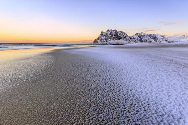 Dawn illuminates the partially snow covered beach of Uttakleiv. Lofoten Islands Norway Europe