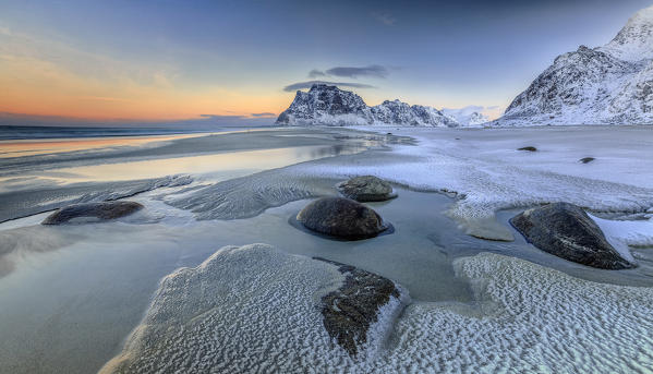 Dawn illuminates the rocks shaped by wind surrounded by fresh snow. Uttakleiv Lofoten Islands Norway Europe