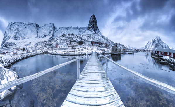 A bridge over the cold sea connects a typical fishing village.  Lofoten Islands Northern Norway Europe
