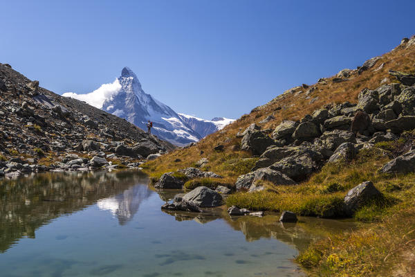 Hiker admires the Matterhorn reflected in the Stellisee at sunrise. Zermatt Canton of Valais Pennine Alps Switzerland Europe