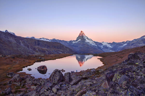 Hikers admire the Matterhorn reflected in the Stellisee at sunrise. Zermatt Canton of Valais Pennine Alps Switzerland Europe