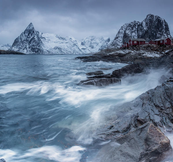 Waves crashing on the cliffs near the houses of the fishermen. Hamnøy. Lofoten Islands Northern Norway Europe