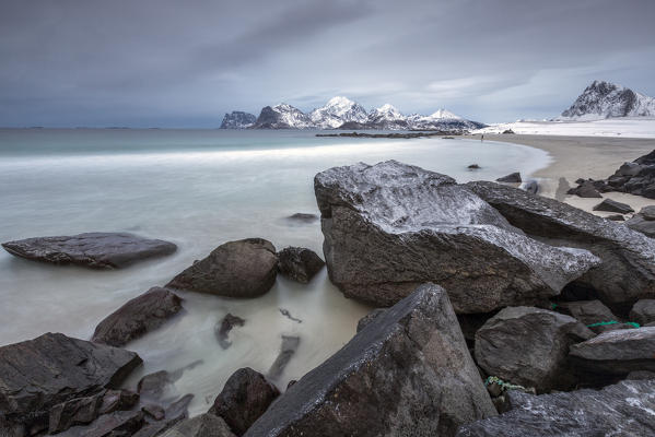 Rocks on the beach partially snow on a cold winter day. Myrland. Lofoten Islands Northern Norway Europe