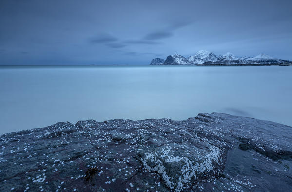 View of the cold sea and snowy mountains from a rock. Myrland. Lofoten Islands Northern Norway Europe