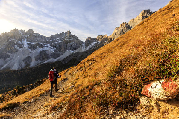 Hiker proceeds toward the group Forcella De Furcia at sunrise. Funes Valley Dolomites South Tyrol Italy Europe