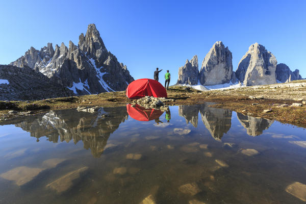 Hikers camped for the night admire the Three Peaks of Lavaredo on awakening. Sesto Dolomites Trentino Alto Adige Italy Europe