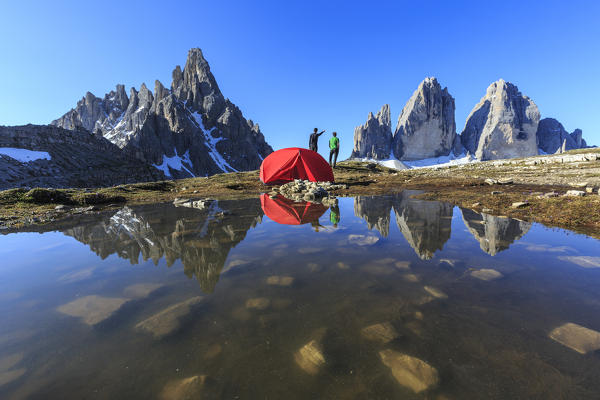 Hikers camped for the night admire the Three Peaks of Lavaredo on awakening. Sesto Dolomites Trentino Alto Adige Italy Europe