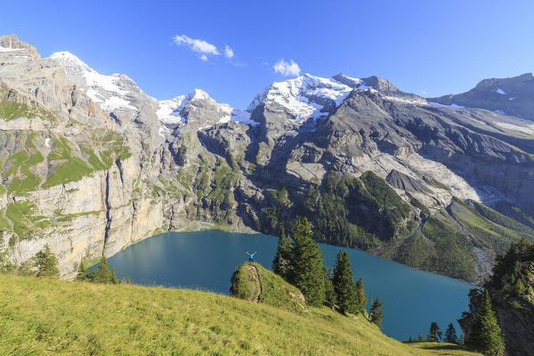 Hiker admires Lake  Oeschinensee Bernese Oberland Kandersteg Canton of Bern Switzerland Europe