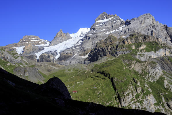 Hiker admires Lake  Oeschinensee Bernese Oberland Kandersteg Canton of Bern Switzerland Europe