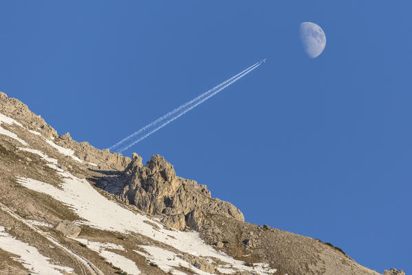 The plane and the moon in the blue sky of Dolomites Auronzo of Cadore Veneto Italy Europe