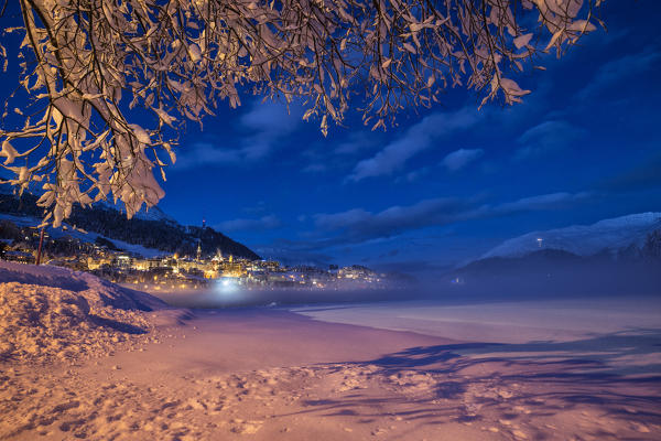 The frozen Inn river and the village of Sankt Moritz at dusk Canton of Grisons Engadine Switzerland Europe