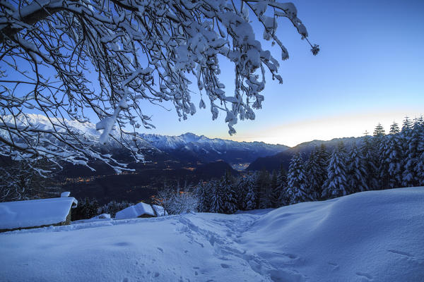 Lights of dusk illuminate the valley and the snow covered huts Tagliate Di Sopra Gerola Valley Valtellina Lombardy Italy Europe