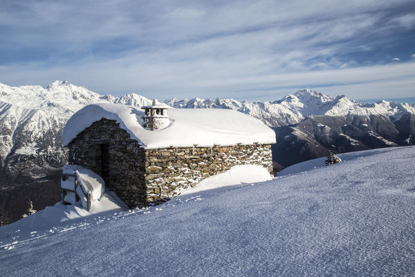 Snow covered hut after a heavy snowfall in the background Masino Valley Olano Valtellina Rhaetian Alps Lombardy Italy Europe