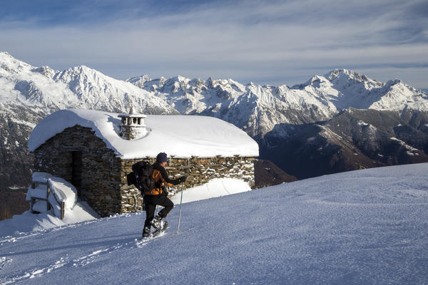 Snowshoe hiker walking with Mount Disgrazia in background Olano Gerola Valley Valtellina Rhaetian Alps Lombardy Italy Europe