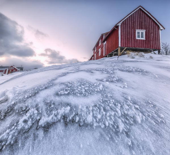 Pink sky on the typical red houses of fishermen called rorbu Henningsvaer Lofoten Islands Northern Norway Europe