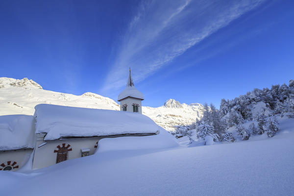 Snowy landscape and the typical church Maloja Canton of Graubünden Engadine Switzerland Europe