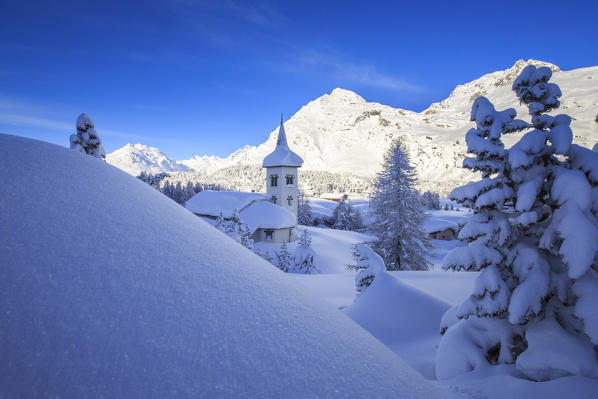 Snowy landscape and the typical church Maloja Canton of Graubünden Engadine Switzerland Europe