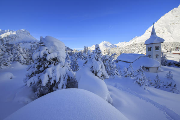 Snowy landscape and the typical church Maloja Canton of Graubünden Engadine Switzerland Europe