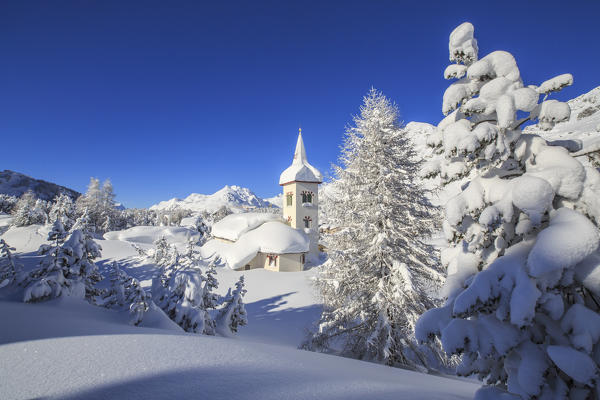 The winter sun illuminate the snowy landscape and the typical church Maloja Canton of Graubünden Engadine Switzerland Europe