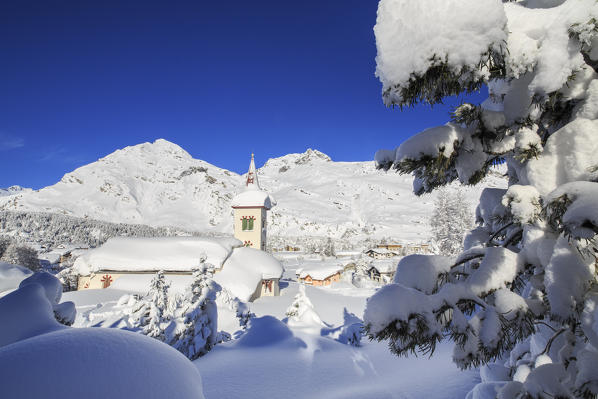 The winter sun illuminate the snowy landscape and the typical church Maloja Canton of Graubünden Engadine Switzerland Europe