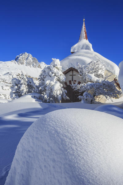 The winter sun illuminate the snowy landscape and the typical church Maloja Canton of Graubünden Engadine Switzerland Europe