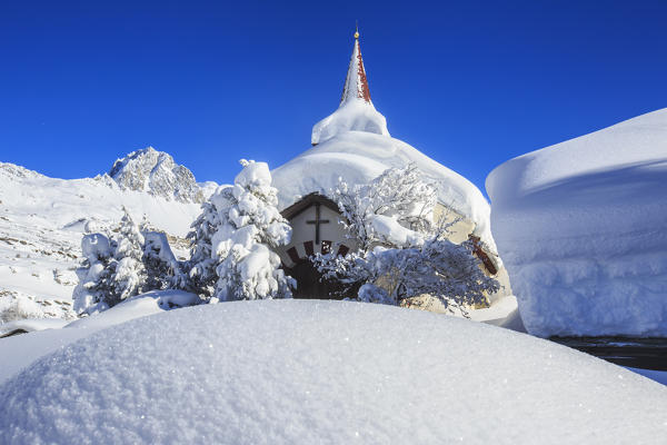 The winter sun illuminate the snowy landscape and the typical church Maloja Canton of Graubünden Engadine Switzerland Europe