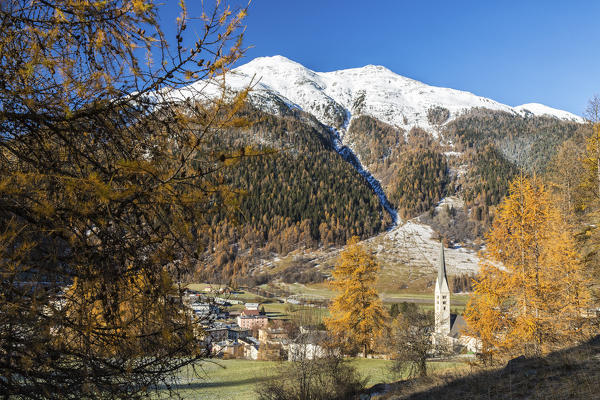 Autumn colors frame the village of Zernez surrounded by woods and snowy peaks Engadine Canton of Graubünden Switzerland Europe