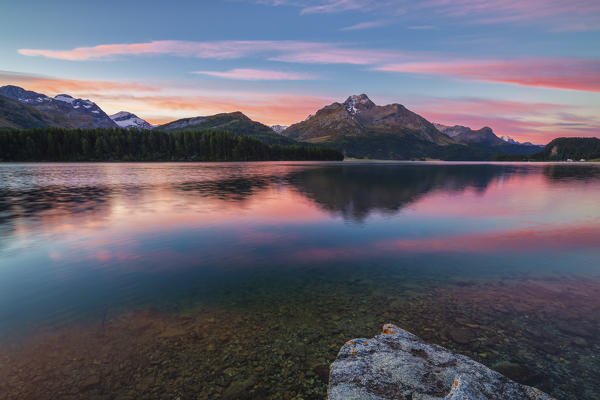Pink sky at dawn illuminates the peaks reflected in Lake Sils Engadine Canton of Graubünden Switzerland Europe