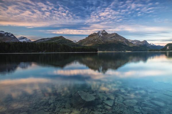 Pink sky at dawn illuminates the peaks reflected in Lake Sils Engadine Canton of Graubünden Switzerland Europe