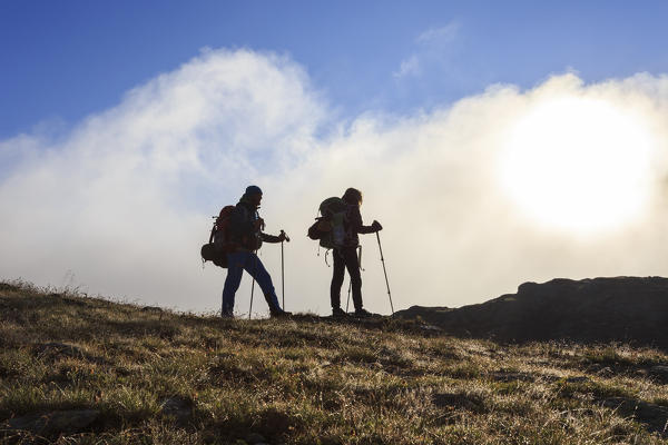 Hikers admire the landscape at dawn Minor Valley High Valtellina Livigno Lombardy Italy Europe
