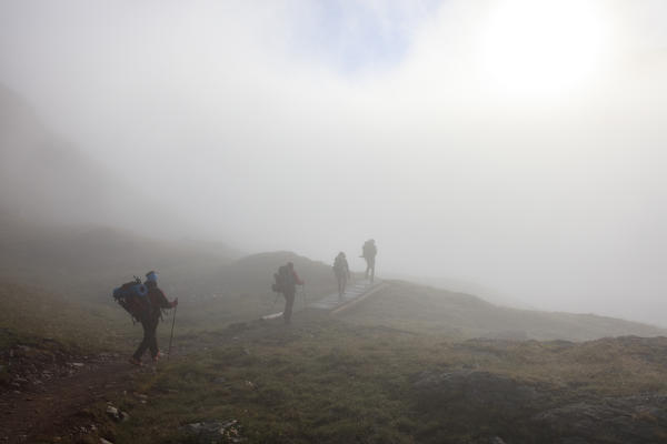 Hikers in the misty landscape at dawn Minor Valley High Valtellina Livigno Lombardy Italy Europe