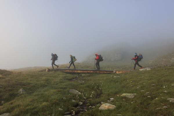 Hikers in the misty landscape at dawn Minor Valley High Valtellina Livigno Lombardy Italy Europe