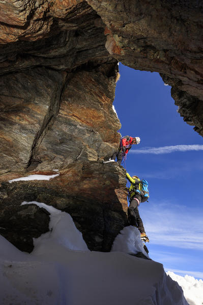 Climbers on the rocks with the snowy peaks of the Alps in the background Stelvio Pass Valtellina Lombardy Italy Europe