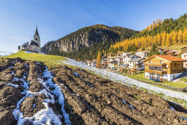 The church of Schmitten surrounded by colorful woods and snow Albula District Canton of Graubünden Switzerland Europe