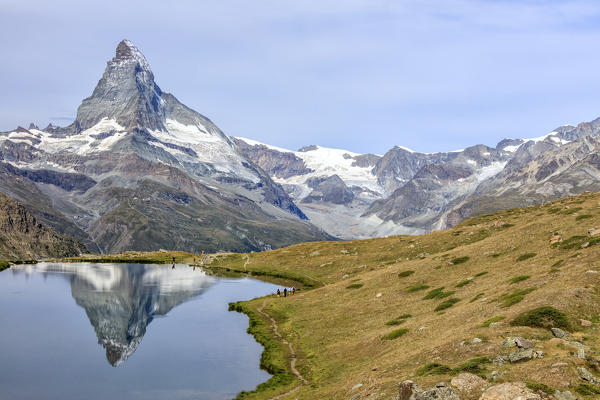 Hikers on the trail to the Matterhorn reflected in Lake Stellisee Zermatt Pennine Alps Canton of Valais Switzerland Europe