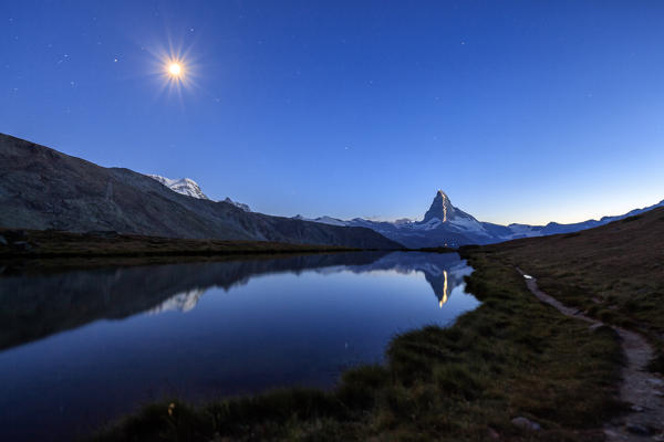 Full moon and Matterhorn illuminated for its anniversary reflected in Lake Stellisee Zermatt Canton of Valais Switzerland Europe