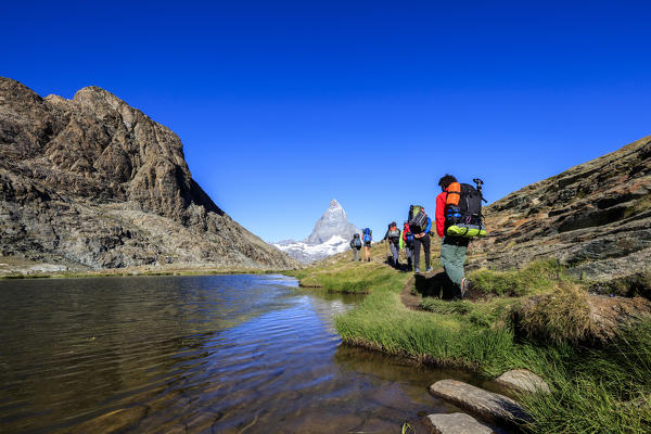 Hikers proceed on the shore of Lake Riffelsee with Matterhorn in the background Zermatt Canton of Valais Switzerland Europe