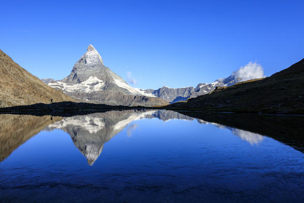 Hiker admires the Matterhorn reflected in Lake Stellisee Zermatt Canton of Valais Pennine Alps Switzerland Europe