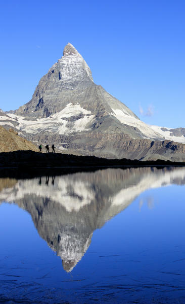 Hikers admire the Matterhorn reflected in Lake Stellisee Zermatt Canton of Valais Pennine Alps Switzerland Europe