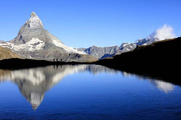 Hikers admire the Matterhorn reflected in Lake Stellisee Zermatt Canton of Valais Pennine Alps Switzerland Europe