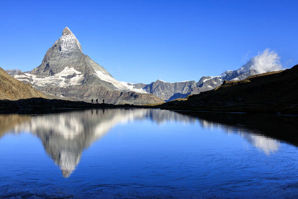 Hikers admire the Matterhorn reflected in Lake Stellisee Zermatt Canton of Valais Pennine Alps Switzerland Europe