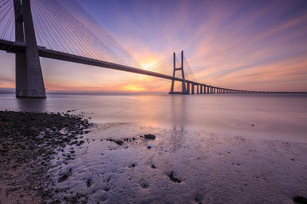 The colors of dawn on  Vasco da Gama Bridge that spans the Tagus River in Parque das Nações Lisbon Portugal Europe