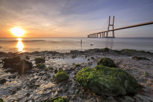 The sun rises on the Vasco da Gama Bridge that spans the Tagus River in Parque das Nações Lisbon Portugal Europe