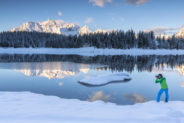 Photographer in action on the shore of Palù Lake where snowy peaks and woods are reflected Malenco Valley Lombardy Italy Europe