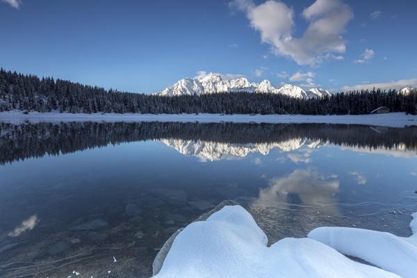 Woods and snowy peaks are reflected in the clear water of Palù Lake Malenco Valley Valtellina Lombardy Italy Europe