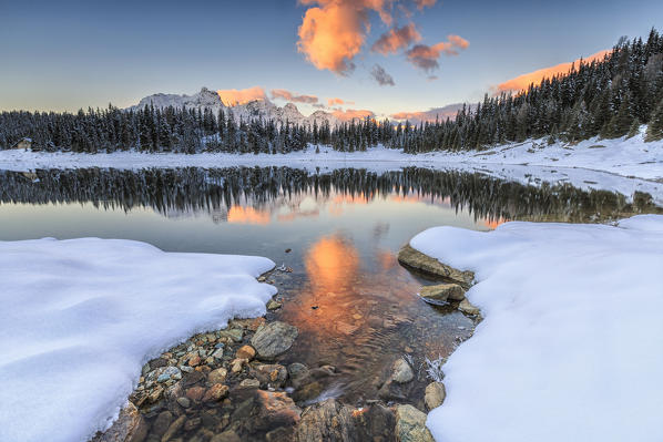 The colors of dawn on the snowy peaks and woods reflected in Palù Lake Malenco Valley Valtellina Lombardy Italy Europe