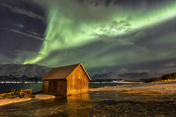 Northern Lights illuminates the wooden cabin at Lenangsoyra Lyngen Alps Tromsø Lapland Norway Europe